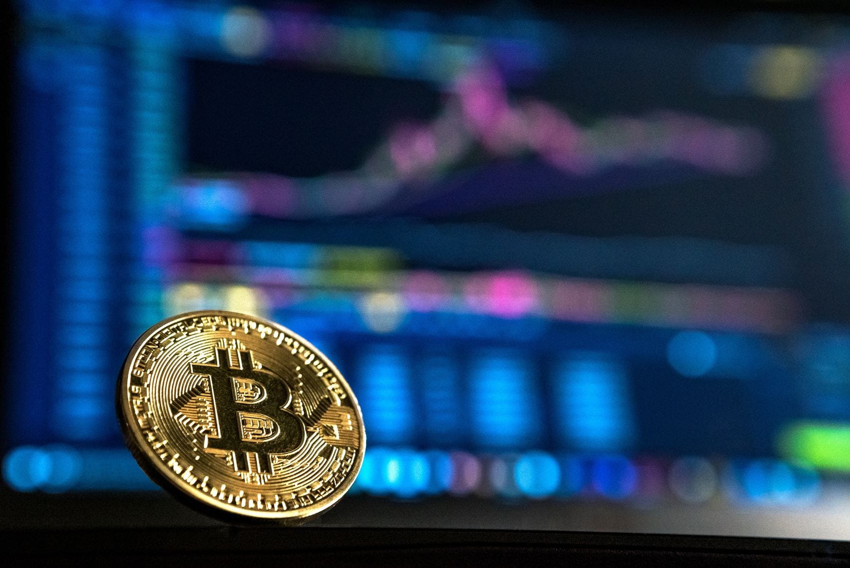 goldene BTC Münze mit unscharfen Charts im Hintergrund